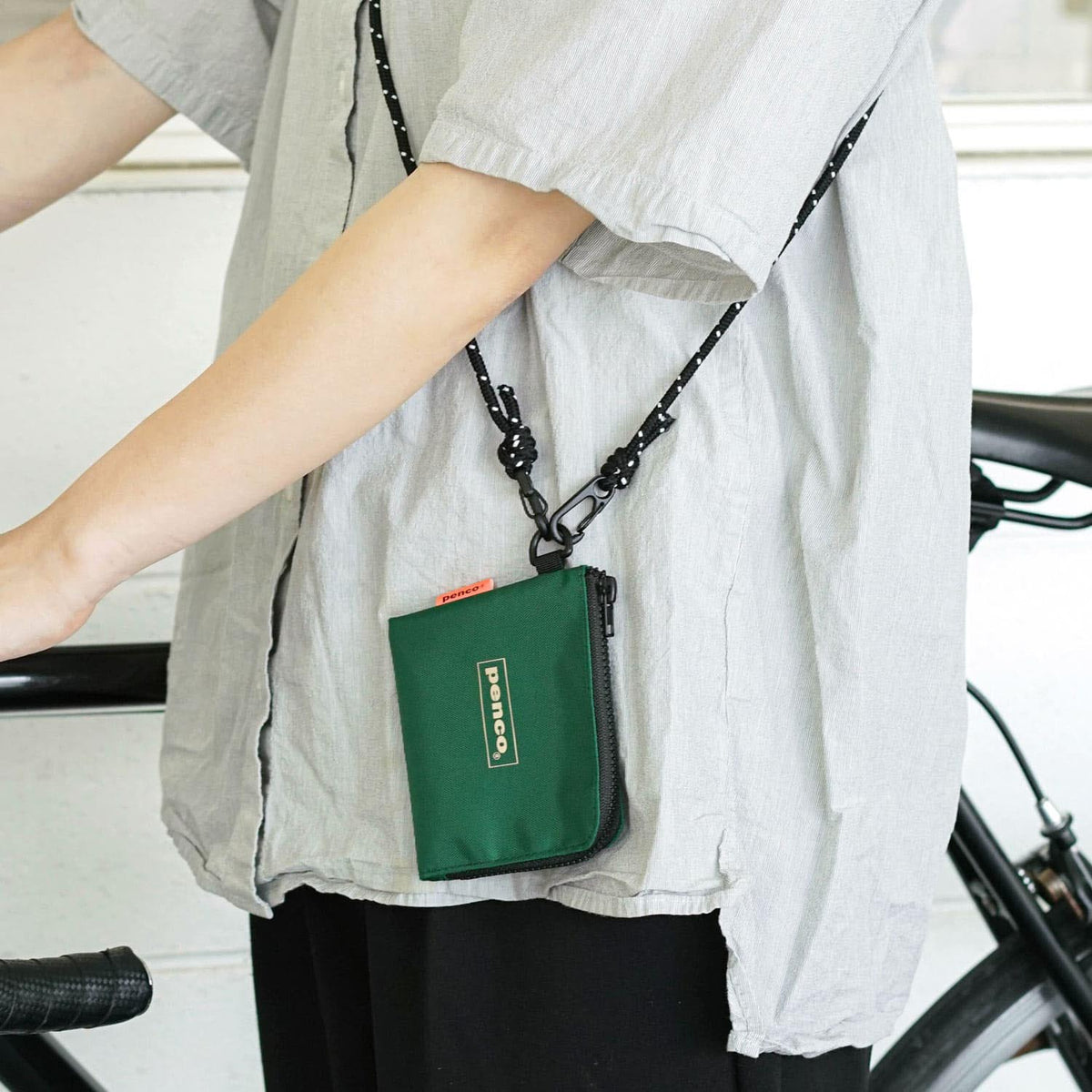 Penco L-Zip Purse Verde scuro indossato con tracolla e agganciato tramite anello laterale